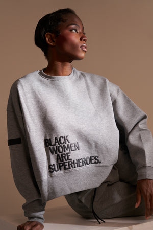 Actively Black Athleisure Wear grey fleece crewneck sweatshirt with "BLACK WOMEN ARE SUPERHEROES" puff print.