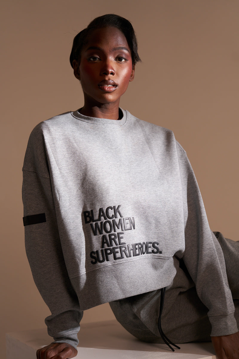 Actively Black Athleisure Wear grey fleece crewneck sweatshirt with "BLACK WOMEN ARE SUPERHEROES" puff print.